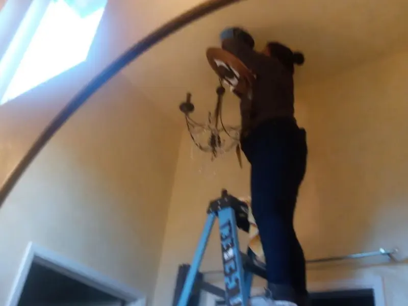 Electrician installing a chandelier in a Perry residence